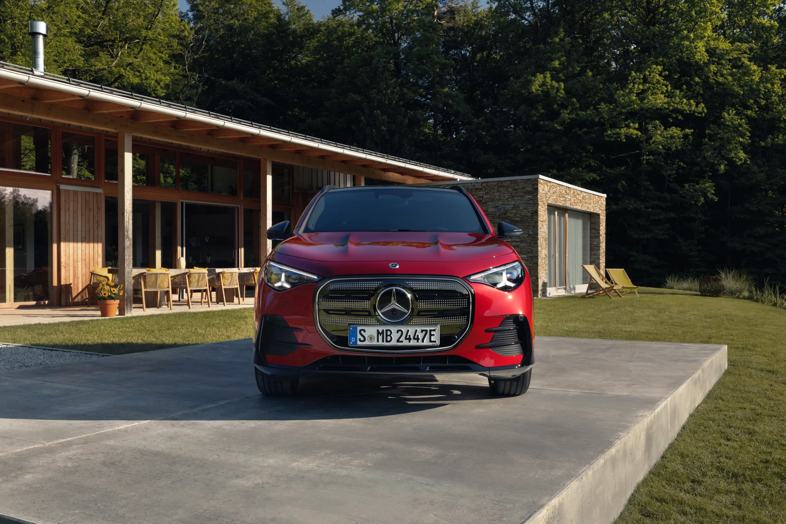 Gla électrique rouge de face avant sur une plateforme grise avec en arrière plan une maison