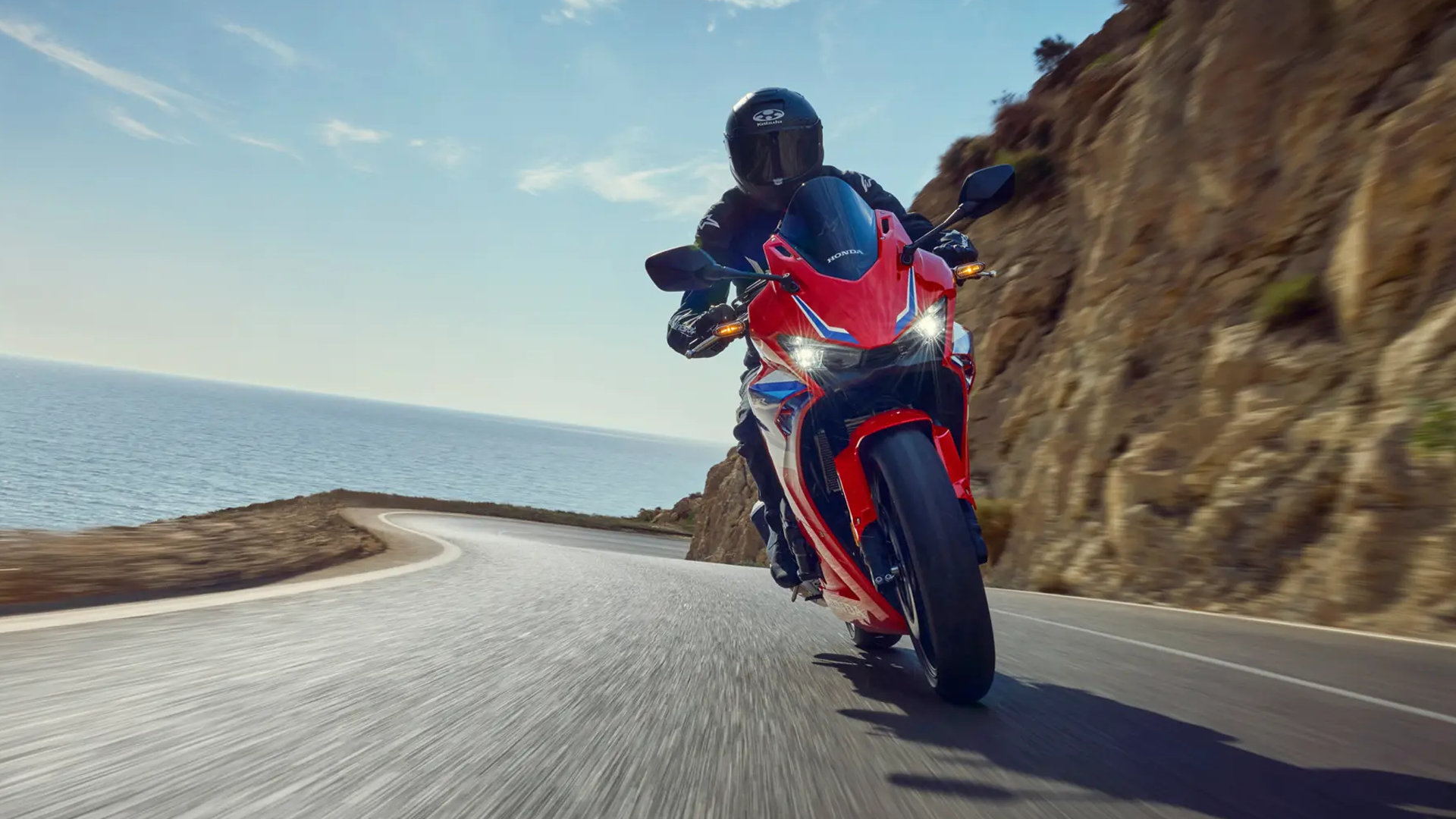 Honda CBR500R en action sur une route sinueuse, pilote équipé