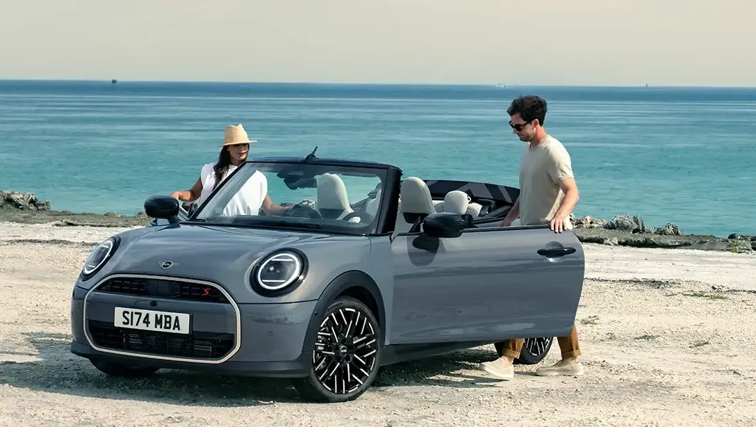 Mini Cooper Cabrio avec toit ouvert sur route ensoleillée